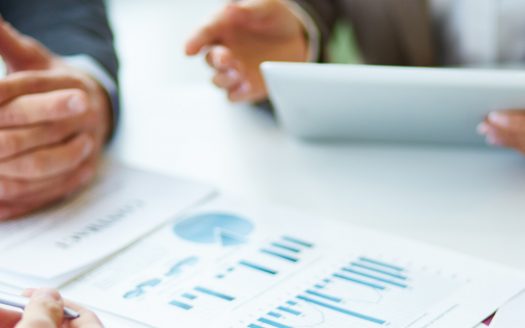 Image of business documents, pen and glasses on workplace during meeting of partners